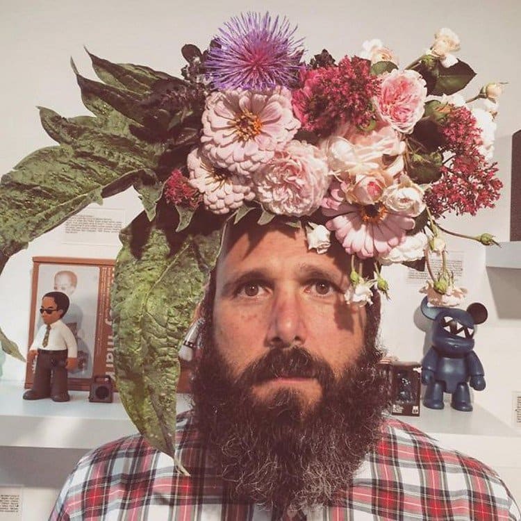hombre con barba con flores en la cabeza