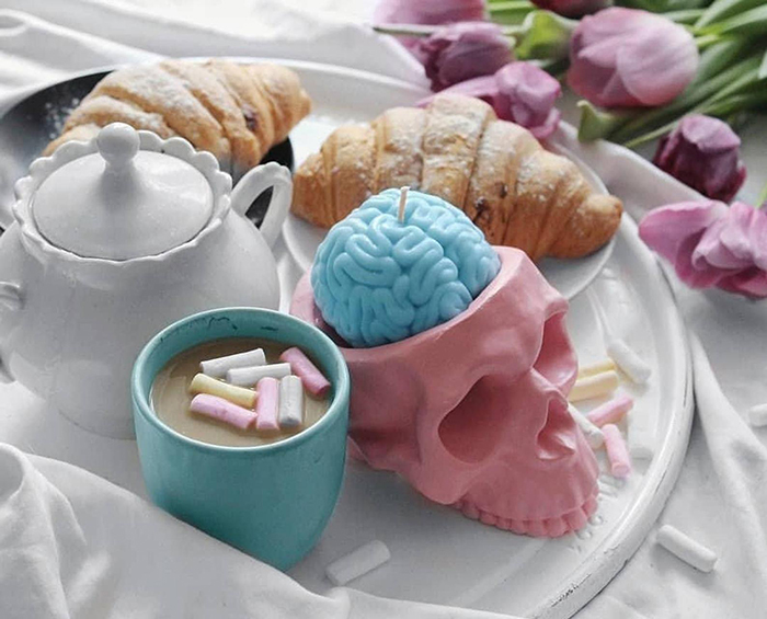 Vela de cerebro humano azul pastel en soporte de calavera rosa